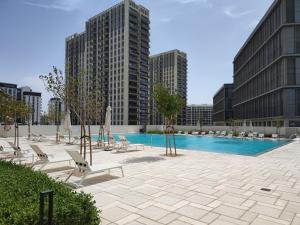 a swimming pool with lounge chairs and buildings at Lovely 1 Bedroom Apartment in Collective 2.0 in Dubai
