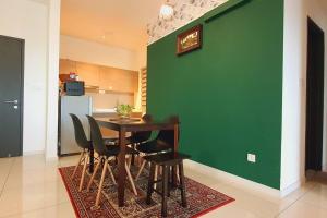 una sala da pranzo con parete verde e tavolo e sedie di Aldridge Residence Cosy Apt @EMIRA Residence a Shah Alam