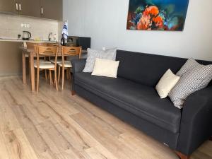 uma sala de estar com um sofá preto e uma cozinha em Sea Towers 2107 em Batumi