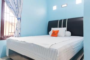 a bed with a black headboard and two orange pillows on it at KoolKost Syariah at Jelutung Jambi in Jambi