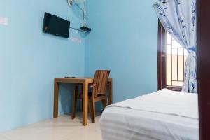 1 dormitorio con escritorio, 1 cama y TV en KoolKost Syariah at Jelutung Jambi en Jambi