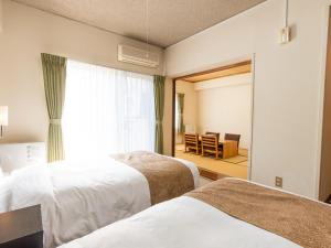 a hotel room with two beds and a mirror at Wisterian Life Club Nojiriko in Shinano