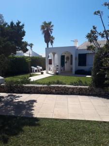 a white house with a palm tree and a sidewalk at Casa Mo in Cala en Bosc