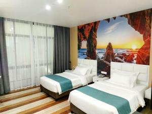 twee bedden in een hotelkamer met een schilderij aan de muur bij Fan's Hotel in Baybay