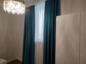a room with a window with blue curtains and a chandelier at Nicole in Uzhhorod