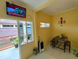 a room with a table and a tv on the wall at Sierra Homestay Malang 3 BR AC in Ngadipuro
