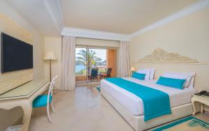 a bedroom with a bed and a desk and a television at Royal Tulip Korbous Bay Thalasso & Springs in Qurbuş