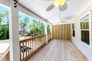a large porch with a ceiling fan and a deck at Beach Cottage South in Dauphin Island