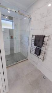 a bathroom with a shower and a towel on a chair at Paihia Apartments in Paihia