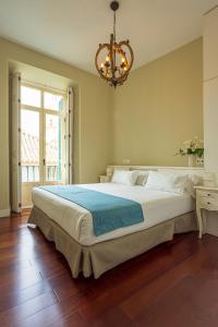 un grande letto in una camera da letto con lampadario a braccio di Madeinterranea Apartments a Málaga