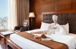 une femme assise sur un lit dans une chambre d'hôtel dans l'établissement Samdi Da Nang Airport Hotel, à Đà Nẵng