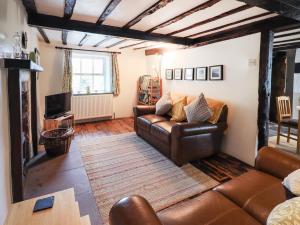 a living room with a leather couch and a television at Blease Garth in Threlkeld