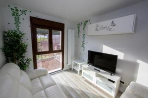ein Wohnzimmer mit einem weißen Sofa und einem TV in der Unterkunft Wind Rose 10 - Moderno duplex a estrenar in San Lorenzo de El Escorial