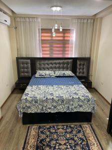 a bedroom with a bed with a blue and white comforter at Flamingo in Dushanbe