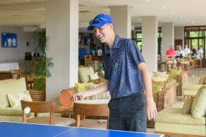 a young man in a blue hat playing a table tennis at San Lameer Villa 2828 - 3 Bedroom Superior - 6 pax - San Lameer Rental Agency in Southbroom +42 photos