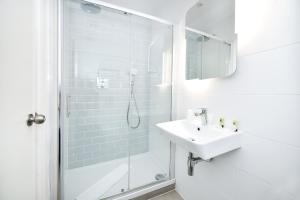 a white bathroom with a sink and a shower at The J Hyde Park in London