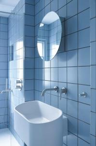 a blue tiled bathroom with a sink and a mirror at Lovely 1-bedroom flat in Chelsea in London