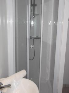 eine Dusche mit Glastür neben einem Waschbecken in der Unterkunft Hotel Tyblomen in Le Faouët
