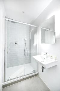 a white bathroom with a shower and a sink at The J Hyde Park in London