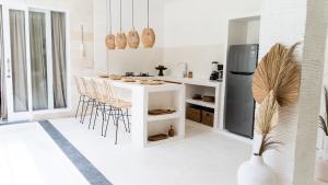 a kitchen with a white counter and chairs and a refrigerator at Villa Diola 2 in Canggu