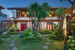 a house with a red door and palm trees at Mahe Garden Inn and Villas by Kamara in Kuta