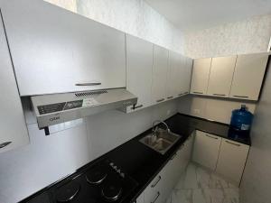 eine kleine Küche mit weißen Schränken und einem Waschbecken in der Unterkunft Hotel Ulug'bek in Buxoro