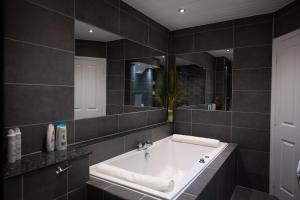 a bathroom with a tub and a large mirror at The Grange Matlock Bath in Matlock