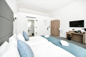 a bedroom with a large white bed with blue pillows at The J Hyde Park in London