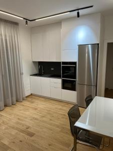 kuchnia z białymi szafkami, stołem i lodówką w obiekcie Adriatico Luxury Apartments w mieście Civitanova Marche