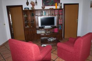 een woonkamer met twee rode stoelen en een televisie bij Casa Sa Carrubedda in SantʼAnna Arresi
