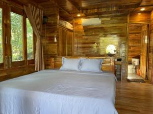 a bedroom with a large bed in a room with wooden walls at COZY HOME PHU QUOC in Phú Quốc