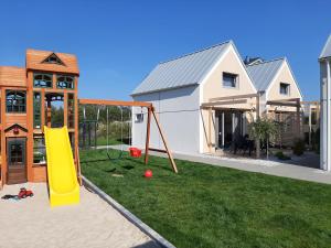 ein Haus mit Spielplatz im Hof in der Unterkunft Wichrowe Domki Plus in Władysławowo