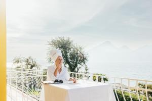 une femme assise à une table devant l'océan dans l'établissement Hotel Orione - Lake Front Hotel, à Brenzone