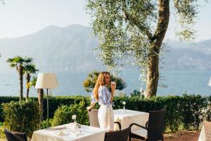 a woman standing at a table at a restaurant at Hotel Orione - Lake Front Hotel in Brenzone sul Garda