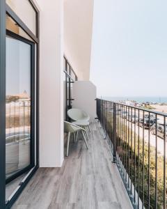 a room with a balcony with a table and chairs at Porto Covo Praia Hotel & SPA in Porto Covo