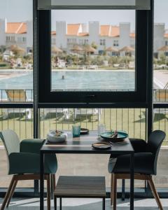 una mesa y sillas con vistas a la piscina en Porto Covo Praia Hotel & SPA en Porto Covo