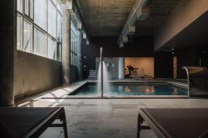 a swimming pool in a building with a fountain at Porto Covo Praia Hotel & SPA in Porto Covo