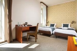 a room with two beds and a desk and a desk at Aparthotel Globus Kraków in Kraków