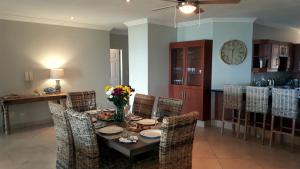 a dining room with a table and chairs and a clock at Trevi 11 in Shelly Beach