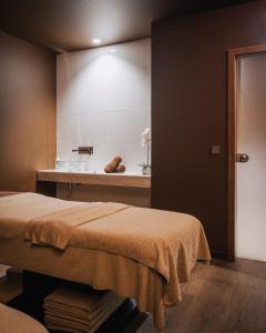 a bathroom with a bed and a sink in a room at Porto Covo Praia Hotel & SPA in Porto Covo