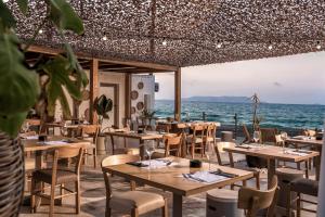 um restaurante na praia com mesas e cadeiras em Enorme Maya Beach Hotel-Adults Only em Gouves