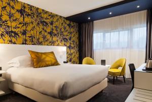una camera d'albergo con letto e scrivania di Hotel Inn Paris CDG Airport - ex Best Western a Roissy en France
