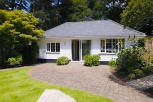 a white house with a brick driveway at Chadham Pines Cottage in Parkstone