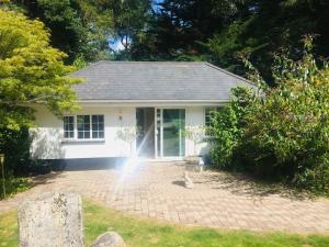 uma casa branca com um pátio de tijolos em frente em Chadham Pines Cottage em Parkstone