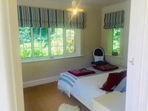 a bedroom with a bed and two windows at Chadham Pines Cottage in Parkstone