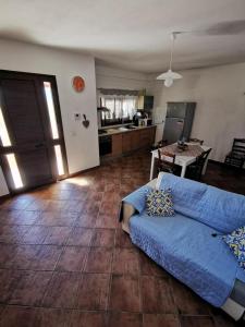 Azzurra’s House Pantelleria في بانتيليريا: غرفة معيشة مع أريكة زرقاء ومطبخ