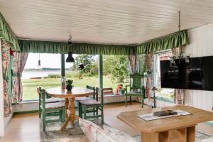 a living room with a table and chairs and a large window at Cottage with own jetty in Ljungbyhed in Ljungbyhed