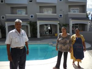 um grupo de três pessoas em pé em frente a uma piscina em Montagu Apartment em Flic-en-Flac