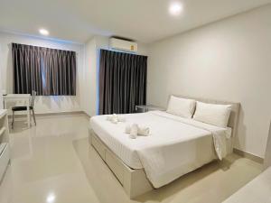 a bedroom with a large white bed and a desk at Donmueang Place Hotel - SHA Plus in Bangkok