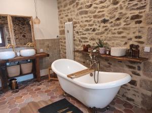 une baignoire dans une salle de bain avec un mur en pierre dans l'établissement La Ville Es Riez Chambre d'hôtes, à Corseul 77 autres photos